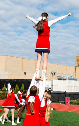 Cheerleaders Holding Teammate In The Air Outside